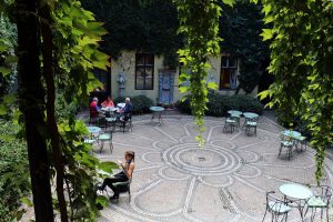The Garden of Építészpince garden bar with green plants and a mosaic floor