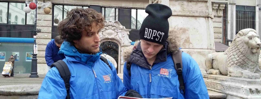 A picture taken of two tour guides wearing our royal blue free tour uniforms in wintertime