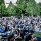 Photo showing a lot of people sitting in the green grass during a festival in the heart of Budapest