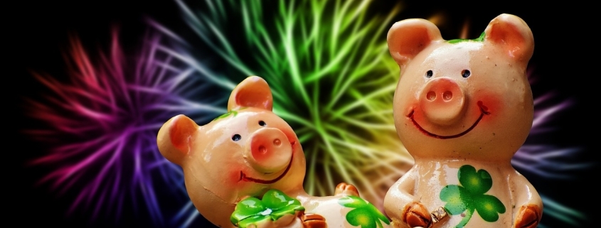 Two pink piglets holding four-leaf clovers that bring luck according to the superstition