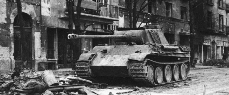 Black and white picture of apartment buildings and a a tank on the streets of the center of Budapest