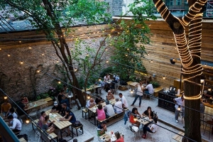 The garden of a popular bar in Budapest with tables, benches, lights and people chatting