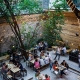 The garden of a popular bar in Budapest with tables, benches, lights and people chatting