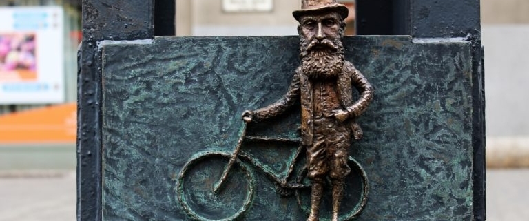 Caption of one of the mini statues of Hungarian sculptor Mihaly Kolodko depicting Theodore Herzl with his bike