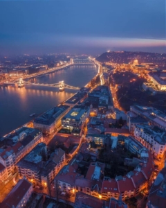 An aerial shot showing Budapest, the river Danube and the Chain bridge lit up on a winter night