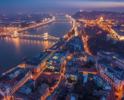 An aerial shot showing Budapest, the river Danube and the Chain bridge lit up on a winter night